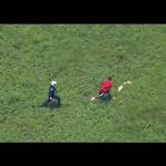 Police officer chasing man across grassy field