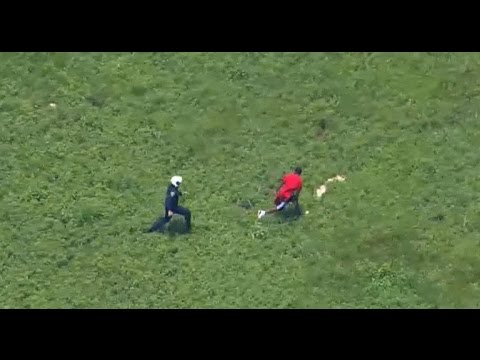 Police officer chasing man across grassy field