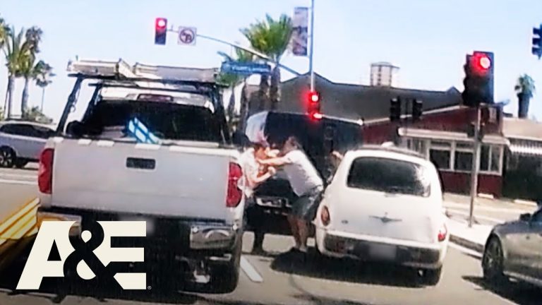 Two people arguing between cars on street.