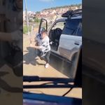 Person with baseball bat beside silver car