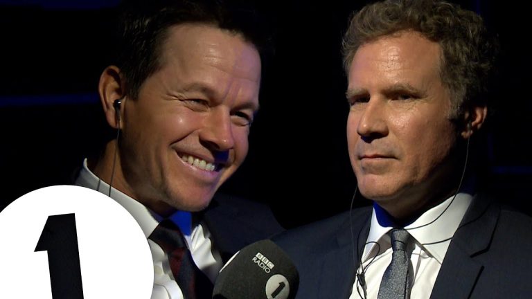 Two men in suits with microphones, smiling.