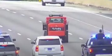 Tractor leading police on highway chase with traffic.