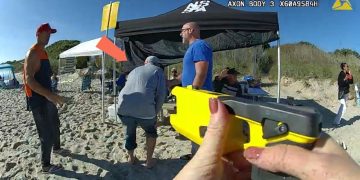 People on beach under tents with equipment.