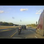 Motorcycle and truck on a highway at sunset.