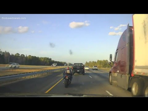 Motorcycle and truck on a highway at sunset.