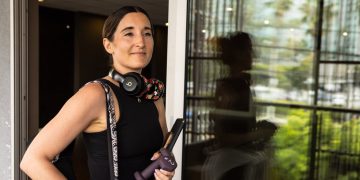 Woman with headphones holding a water bottle.