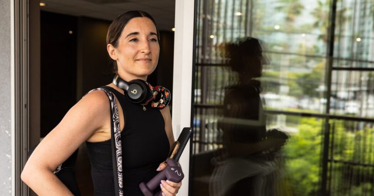 Woman with headphones holding a water bottle.