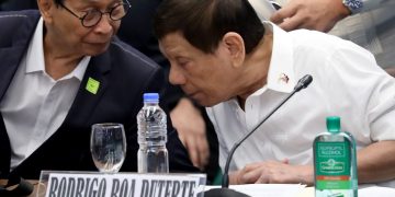 Two men conversing at a conference table.