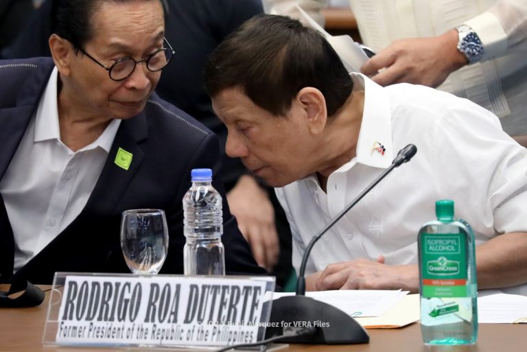 Two men conversing at a conference table.