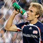 Soccer player drinks water during game break.