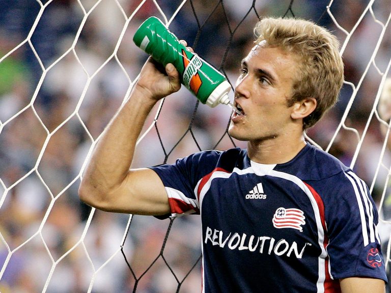 Soccer player drinks water during game break.