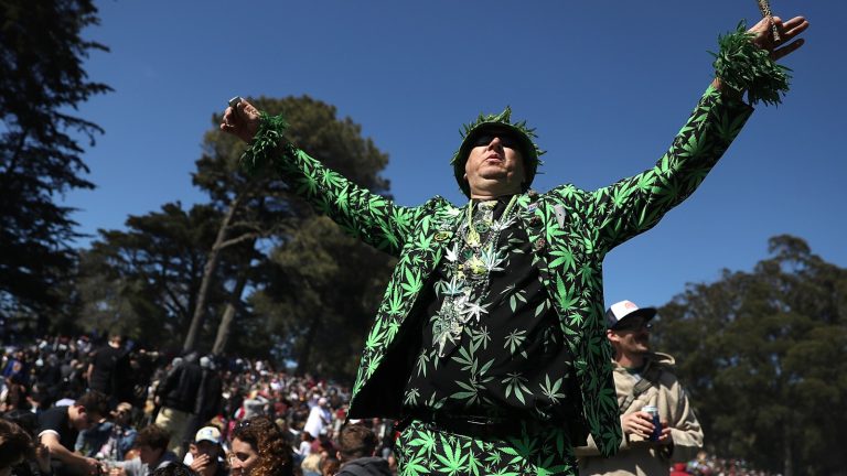 Person in cannabis-themed suit at outdoor gathering.