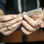 Person rolling a cannabis joint with paper