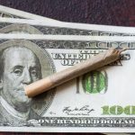 Rolled cigarette on hundred dollar bills