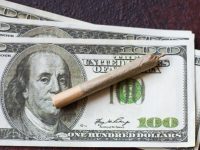 Rolled cigarette on hundred dollar bills