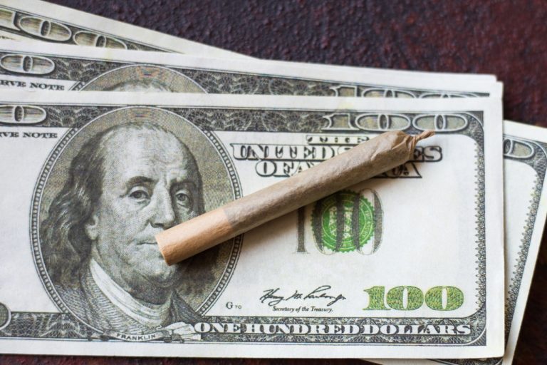 Rolled cigarette on hundred dollar bills