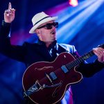 Musician in hat playing guitar on stage