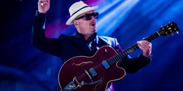 Musician in hat playing guitar on stage