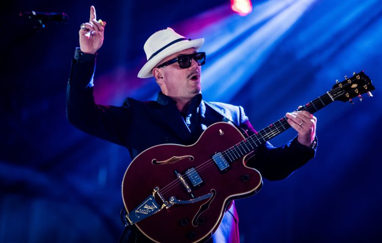 Musician in hat playing guitar on stage