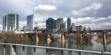 Downtown Austin skyline over river with bridge.