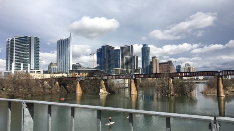 Downtown Austin skyline over river with bridge.