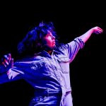 Person dancing under colorful stage lights.