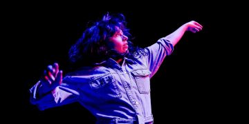 Person dancing under colorful stage lights.