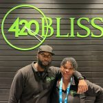 Two employees in front of 420 Bliss sign.