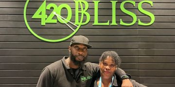 Two employees in front of 420 Bliss sign.