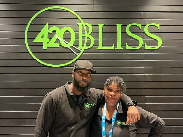 Two employees in front of 420 Bliss sign.