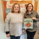 Two people holding animal poop book indoors.