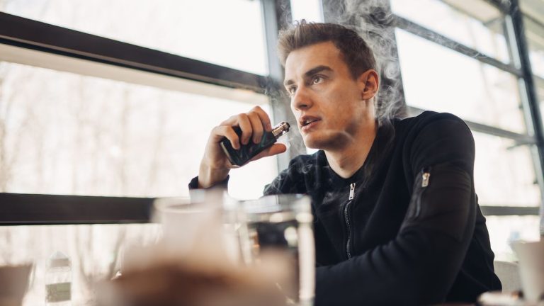 Person vaping indoors near window.