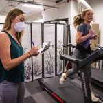 Woman running on treadmill, another writing on clipboard.