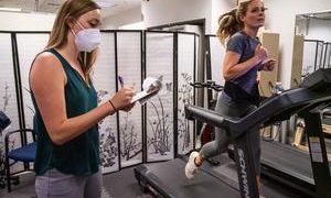 Woman running on treadmill, another writing on clipboard.