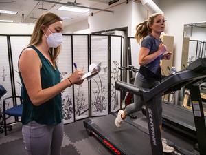 Woman running on treadmill, another writing on clipboard.