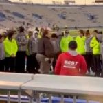 Team huddle on sports field during sunset gathering.