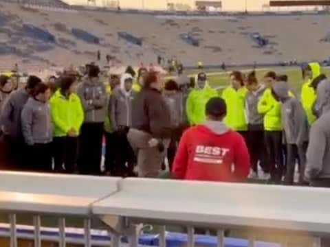 Team huddle on sports field during sunset gathering.