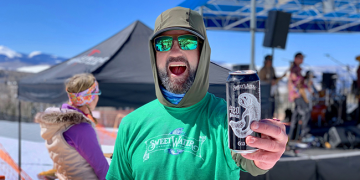 Man enjoying outdoor event with SweetWater beer can.