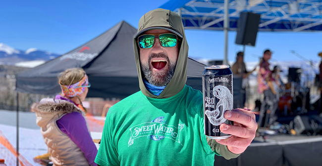 Man enjoying outdoor event with SweetWater beer can.