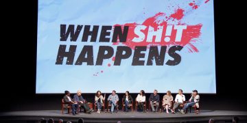 Panel discussion in front of 'When Sh!t Happens' screen.