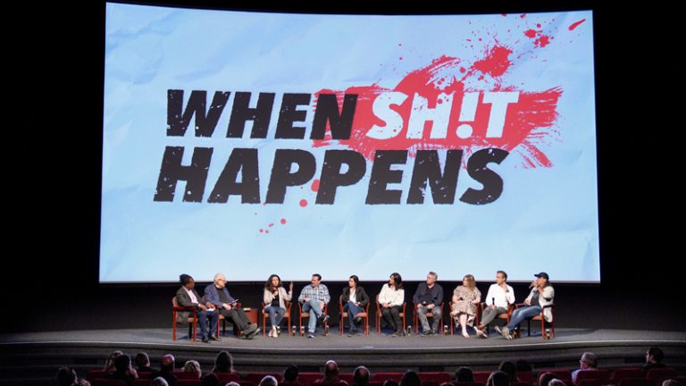 Panel discussion in front of 'When Sh!t Happens' screen.