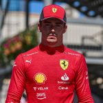 Ferrari driver in red uniform and cap outdoors.