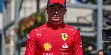 Ferrari driver in red uniform and cap outdoors.