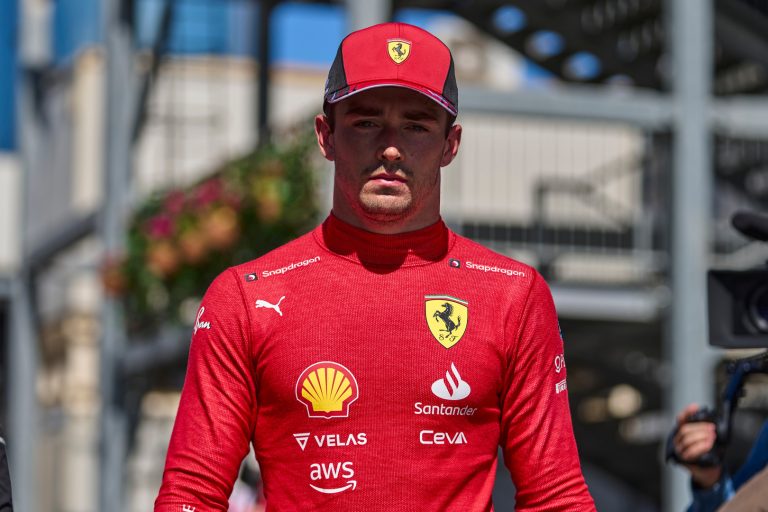 Ferrari driver in red uniform and cap outdoors.