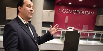 Man explaining in front of Cosmopolitan display case.