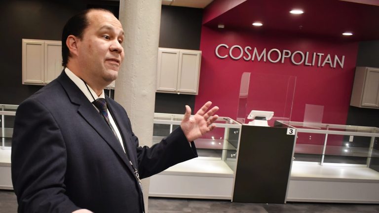 Man explaining in front of Cosmopolitan display case.