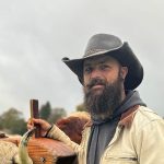 Man in cowboy hat, overcast sky background