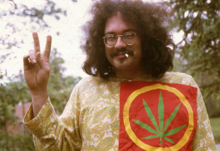 Person holding peace sign with cannabis leaf shirt