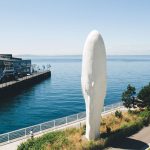 Waterfront sculpture near pier and cruise ship