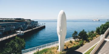 Waterfront sculpture near pier and cruise ship